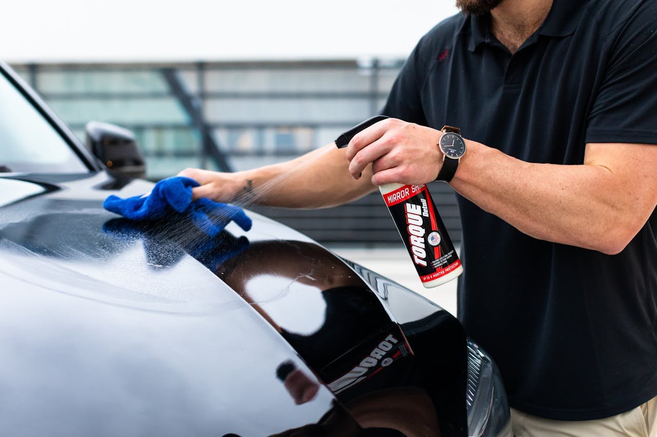 The Art of Drawing Readers In: Your attractive post title goes here A man cleaning a black car hood with a spray and microfiber cloth.